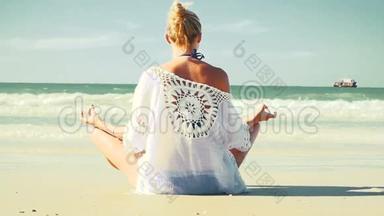 年轻的金发女人在海滩上做瑜伽